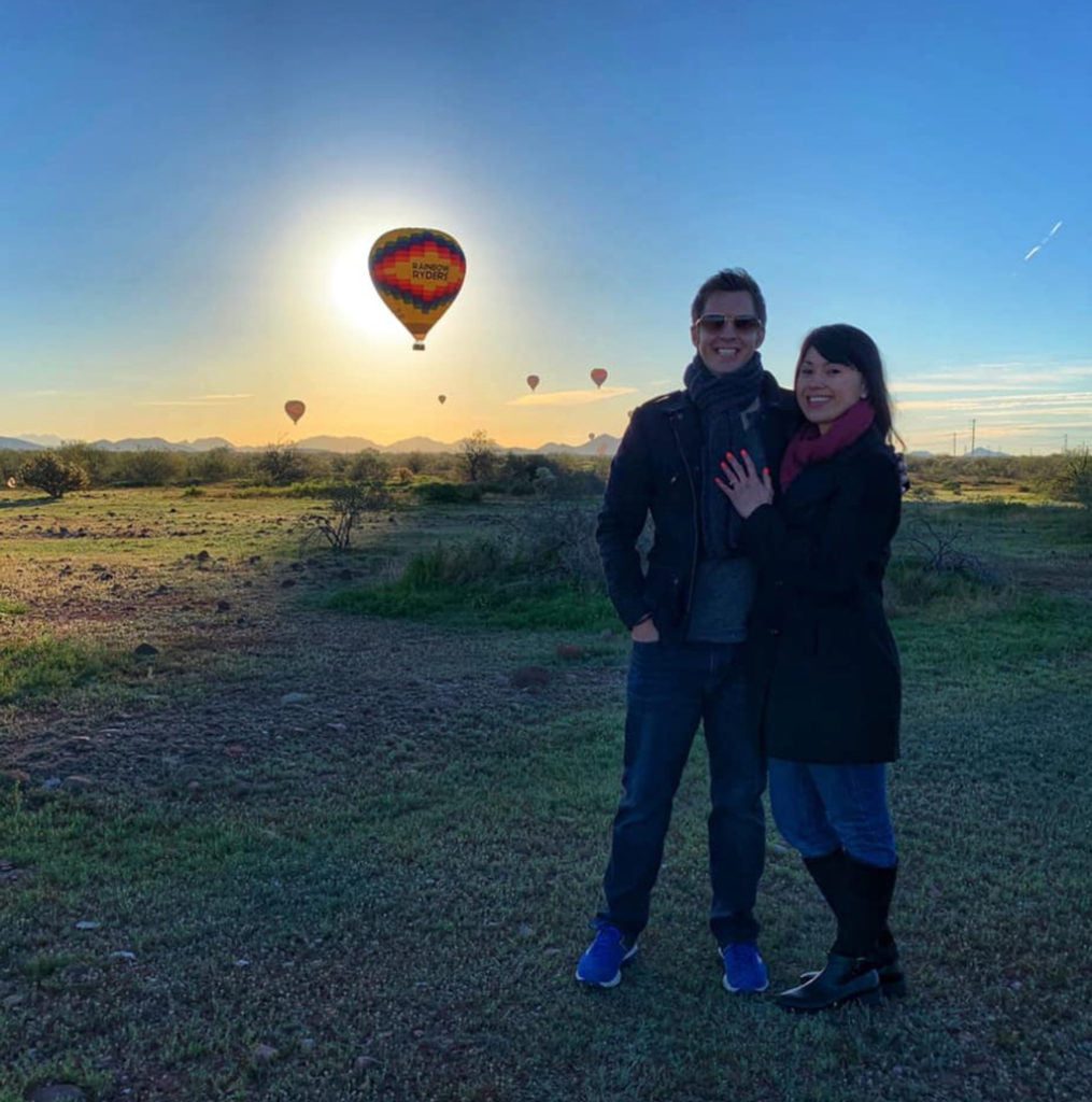 Couple posing in front of hot air balloons in flight