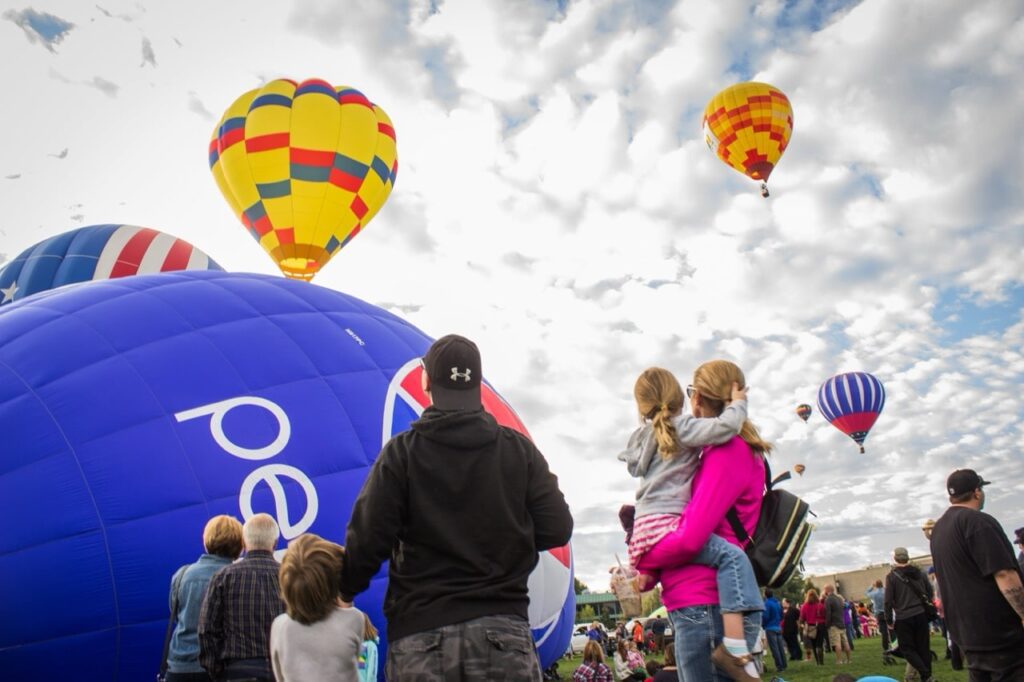 Family staring up at hot air balloons during takeoff