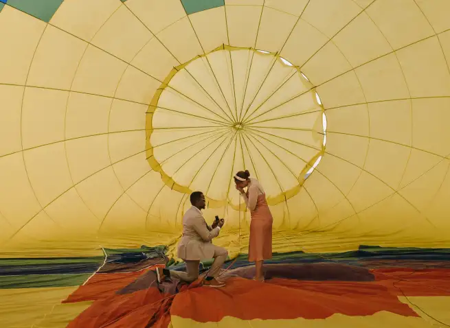 Man proposing to his partner in front of hot air balloon envelope